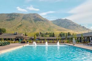 a pool with water fountains in front of a mountain at The Virginian Lodge, an Outbound Hotel in Jackson
