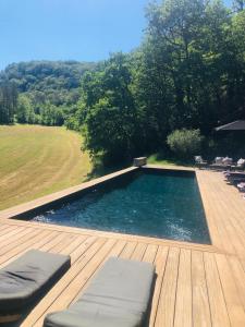 a swimming pool on a wooden deck with chairs at Le Mas de Laval in Saint-Cirq-Lapopie