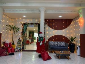 a santa claus standing in a lobby with christmas decorations at Hotel Novoleste in Senhor do Bonfim