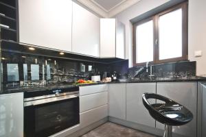 a kitchen with white cabinets and a black chair at Siedmiogrodzka 7 Serviced Apartments by P&O in Warsaw