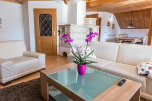 a living room with a couch and a table with purple flowers at Ferienwohnung Maria in Liggersdorf