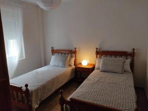 2 Betten in einem Zimmer mit einer Lampe auf einem Tisch in der Unterkunft Mi Piso en Béjar in Béjar