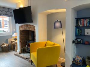 a living room with a yellow chair and a fireplace at Witcroft Cottage in Pershore