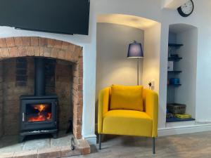 a yellow chair in a living room with a fireplace at Witcroft Cottage in Pershore
