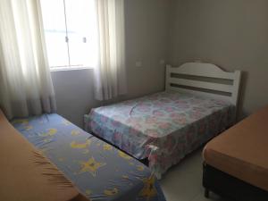 ein kleines Schlafzimmer mit einem Bett und einem Fenster in der Unterkunft Recanto Maria Flor in Guarujá