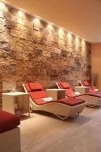 a lobby with chairs and tables and a stone wall at GH Palazzo Suite & SPA in Livorno