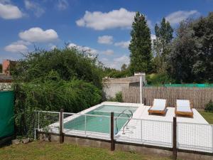 una pequeña piscina con 2 tumbonas junto a una valla en Cabaña La Antonia 1 en La Granja