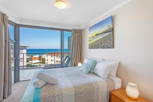 a bedroom with a bed and a view of the ocean at Salt on Kings Apartments in Caloundra