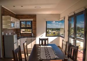 eine Küche mit einem Tisch mit Stühlen und einem großen Fenster in der Unterkunft Terrazas del Ceferino in Sierra de la Ventana