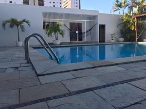 a swimming pool with a hand rail next to a building at Casa agradável com excelente piscina para toda a família in João Pessoa