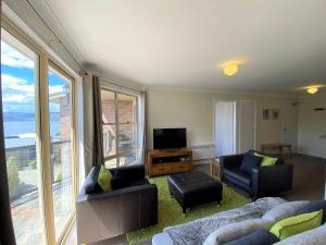 a living room with a couch and chairs and a tv at Caribou 3 Views over Lake Jindabyne with Wifi in Jindabyne