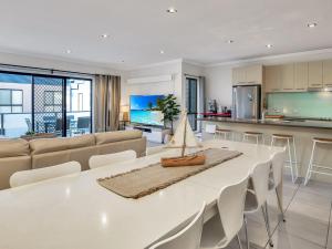 a kitchen and living room with a white table and chairs at Starfish Sands in Cowes