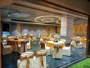 un salón de banquetes con mesas y sillas decoradas en blanco y dorado en Hotel BMD The Grand en Bhīlwāra