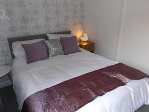 Cama con sábanas y almohadas de color púrpura y blanco en The Granby hotel, en Whitby