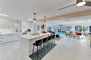 a kitchen with white cabinets and a bar with stools at Anything Is Possible in Sarasota