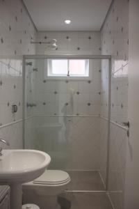a bathroom with a shower and a toilet and a sink at Casa em Condomínio, PÉ NA AREIA, praia Guaratuba in Bertioga