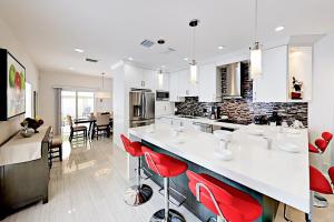 a white kitchen with red bar stools in it at Pompano Retreat in Pompano Beach