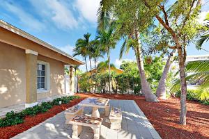 a patio with benches and palm trees next to a house at Pompano Retreat in Pompano Beach