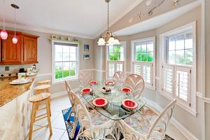 cocina y comedor con mesa de cristal y sillas en Poseidons Cabana en Saint Augustine