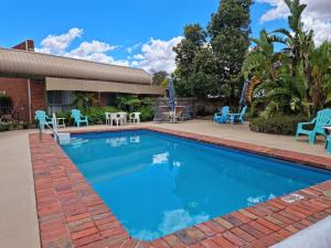 a swimming pool with blue chairs and tables at Tooleybuc Club Motor Inn in Tooleybuc