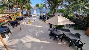 un grupo de mesas y sillas con sombrilla en la playa en Hotel Machos Mahahual en Mahahual