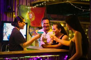 un grupo de personas sentadas en un bar con bebidas en Perezoso Hostel, en Rurrenabaque