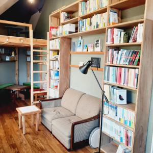 a living room with a couch and bookshelves at Iruka Hostel in Toyama