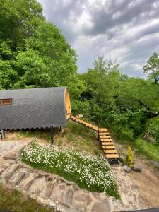 a building with a gray roof with stairs and white flowers at Woodhide - Cottages near Batumi, Georgia in Zeda Ch'khutunet'i