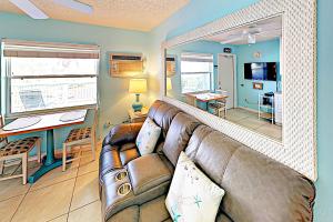 uma sala de estar com um sofá de couro e um espelho em Breezy Belleair 5E em Clearwater Beach