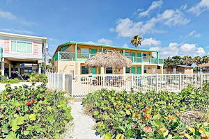 a house with a white fence and a straw umbrella at Breezy Belleair 5E in Clearwater Beach