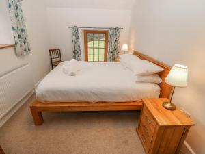 a bedroom with a bed and a table with a lamp at Peniarth Ganol in Tywyn