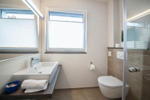 baño con lavabo y aseo y ventana en Pension An Bord en Varel