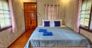 a bedroom with a large bed with blue sheets at TA YAI HOMESTAY (ตา ยาย โฮมสเตย์) in Ko Kood