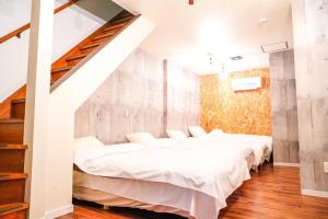 a bedroom with white beds and a wooden wall at ONE HOSTEL Himeji in Himeji