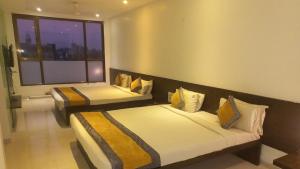 two beds in a room with a window at Hotel Golden View in Shirdi