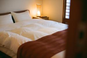 a bedroom with a white bed and a lamp at Hakonowa in Hakone