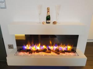 a white fireplace with flames and a bottle of champagne at kleine Düne in Cuxhaven