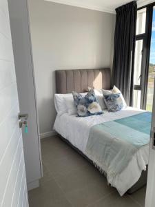 a bedroom with a bed with pillows and a window at Flat 14 Block 6 Bellamare in Port Elizabeth