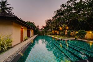 a swimming pool in front of a house at night at The Spice Trail in Arugam Bay