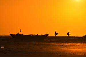 a boat on the beach at sunset with two people and a camel at The Spice Trail in Arugam Bay