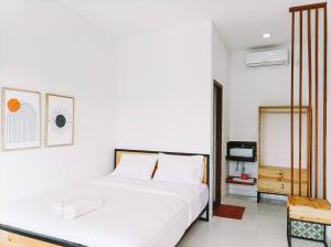 a white bedroom with a bed and a tv at Ancala Uluwatu in Uluwatu