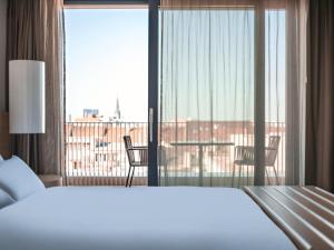 a bedroom with a bed and a view of a balcony at Pullman Basel Europe in Basel