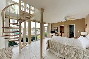 a bedroom with a bed and a spiral staircase at BeauMer 102B in Naples +32 photos