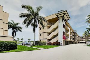 a building with a palm tree in front of it at BeauMer 102B in Naples