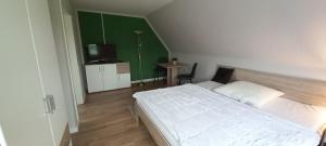 ein Schlafzimmer mit einem weißen Bett und einer grünen Wand in der Unterkunft zum Kranichblick in Glinstedt