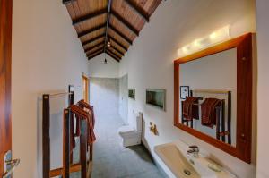 a bathroom with a sink and a mirror and a toilet at The Spice Trail in Arugam Bay