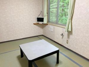 een lege kamer met een tafel en een raam bij 五岳庵 in Shinano