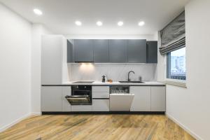 uma cozinha com armários a preto e branco e piso em madeira em The Central Park Residence em Cluj-Napoca