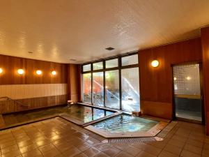 中津川温泉　ホテル花更紗 في Ochiai: غرفة كبيرة مع تجمع للمياه في الأرض
