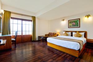 ein Hotelzimmer mit einem großen Bett und einem Schreibtisch in der Unterkunft Summit Ttakshang Residency Hotel & Spa in Gangtok